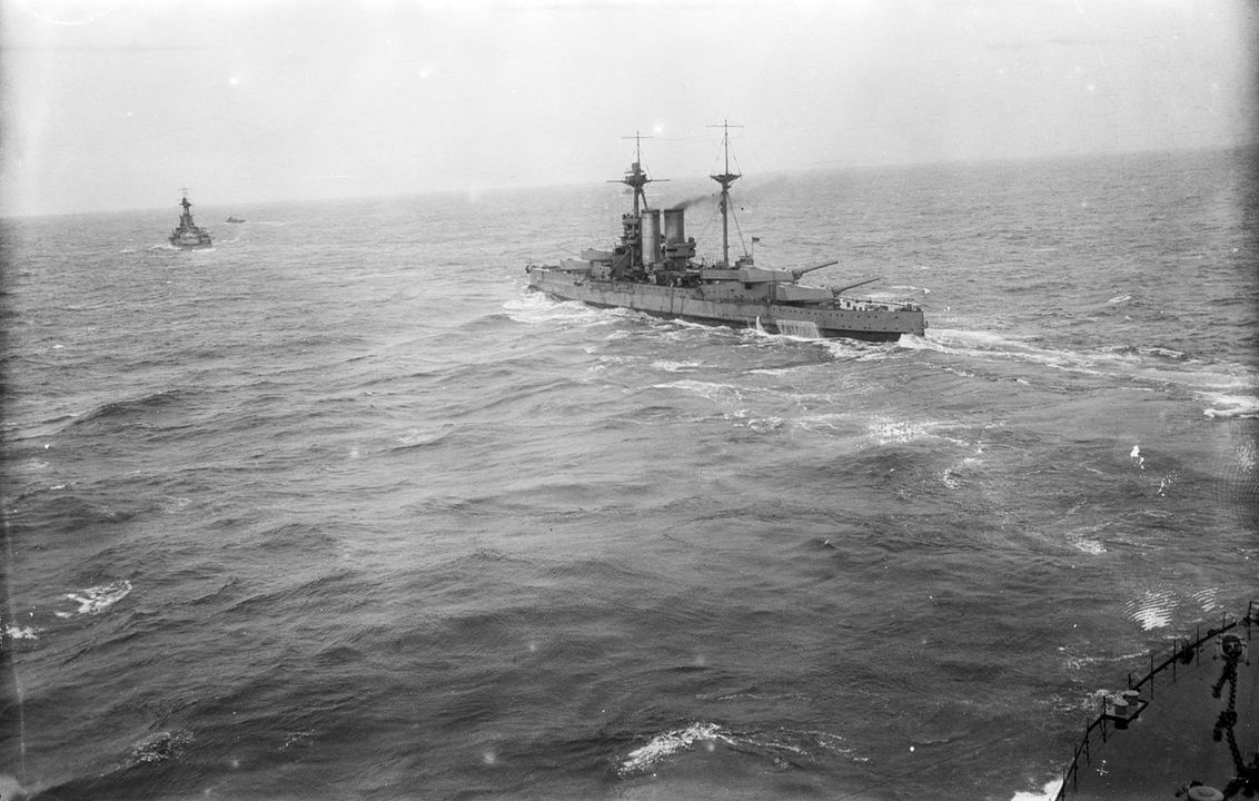 Hải đoàn Thiết giáp hạm số 5 được chụp từ mạn trái của thiết giáp hạm lớp Queen Elizabeth HMS Warspite (1913), chụp từ tàu chị em HMS Queen Elizabeth (1913). Góc nhìn từ thượng tầng phía trước của Queen Elizabeth, hướng về phía trước qua sàn mũi tàu. Các khẩu pháo 15 inch của Warspite được hướng ra mạn phải cho thấy cuộc huấn luyện pháo binh sắp diễn ra và con tàu vừa thực hiện một cú ngoặt gấp sang mạn trái, triển khai cùng các đồng đội trong phi đội từ hàng sang cột. Phía xa hơn, cũng vừa thực hiện di chuyển tương tự, là HMS Barham (1914). Con tàu nhỏ ở phía xa dường như là một tàu khu trục dẫn đầu đội tàu.