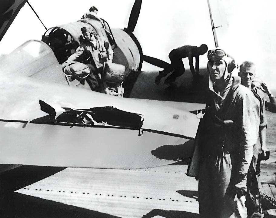 Một phi công của VB-13 kiểm tra các vết hư hại do hỏa lực phòng không trên máy bay của mình, trên boong USS Franklin (CV-13) sau khi tham gia tấn công Musashi vào ngày 24 tháng 10 năm 1944. Ở hậu cảnh, có thể thấy xạ thủ của anh ta đang mang cả hai chiếc dù trên cánh phải của chiếc Helldiver. VB-13 đã hoạt động từ tàu sân bay biệt danh “Big Ben” trong giai đoạn từ tháng 7 đến tháng 10 năm 1944. (Peter Mersky)