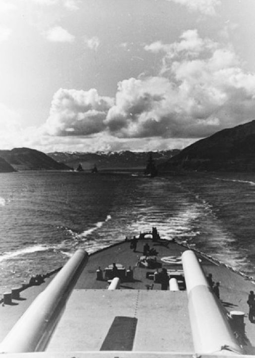 Bismarck và Tirpitz được trang bị dàn pháo chính gồm tám khẩu pháo 15 inch. Bức ảnh này cho thấy Tirpitz đang dẫn đầu một đội hình chiến hạm rời khỏi một vịnh hẹp Na Uy, với hai tháp pháo 15 inch phía sau hiện rõ trong ảnh. Khi chuyển sang pháo 16 inch trên lớp H-39, người Đức đã nâng cấp từ loại pháo 15 inch bắn đạn nặng 1.764 pound lên loại pháo có đạn nặng 2.271 pound, mang lại khả năng xuyên phá lớn hơn tương ứng. Nếu họ áp dụng thiết kế tháp pháo ba nòng cho dàn pháo chính của thiết giáp hạm, trọng lượng hệ thống pháo sẽ được tiết kiệm, nhưng họ vẫn lựa chọn duy trì cấu hình tháp pháo đôi. (Naval History and Heritage Command)