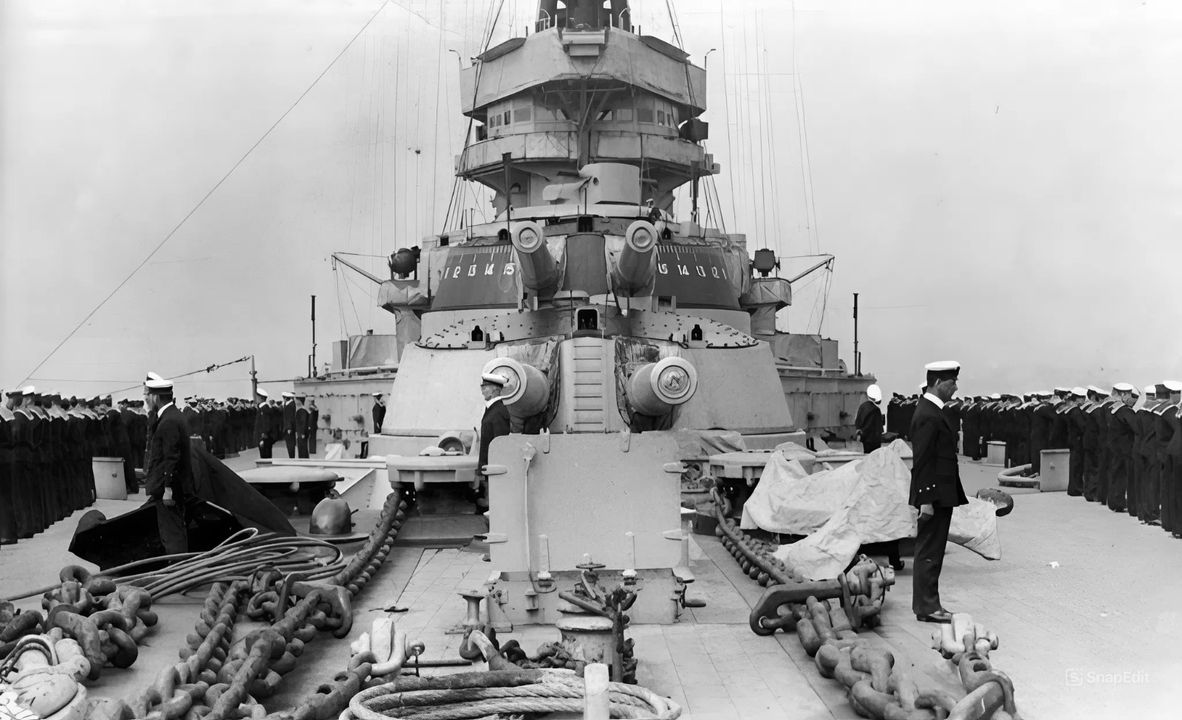 Mũi tàu (forecastle) của thiết giáp hạm HMS King George V, tàu cùng lớp mang tên của mình, khi thủy thủ xếp hàng dọc mạn tàu chào đón Vua George V sau khi hạm đội Đức đầu hàng năm 1918. Bức ảnh cho thấy thang chia độ ngắm bắn được sơn bên mạn tháp pháo “B”, nhằm đơn giản hóa việc điều khiển hỏa lực.