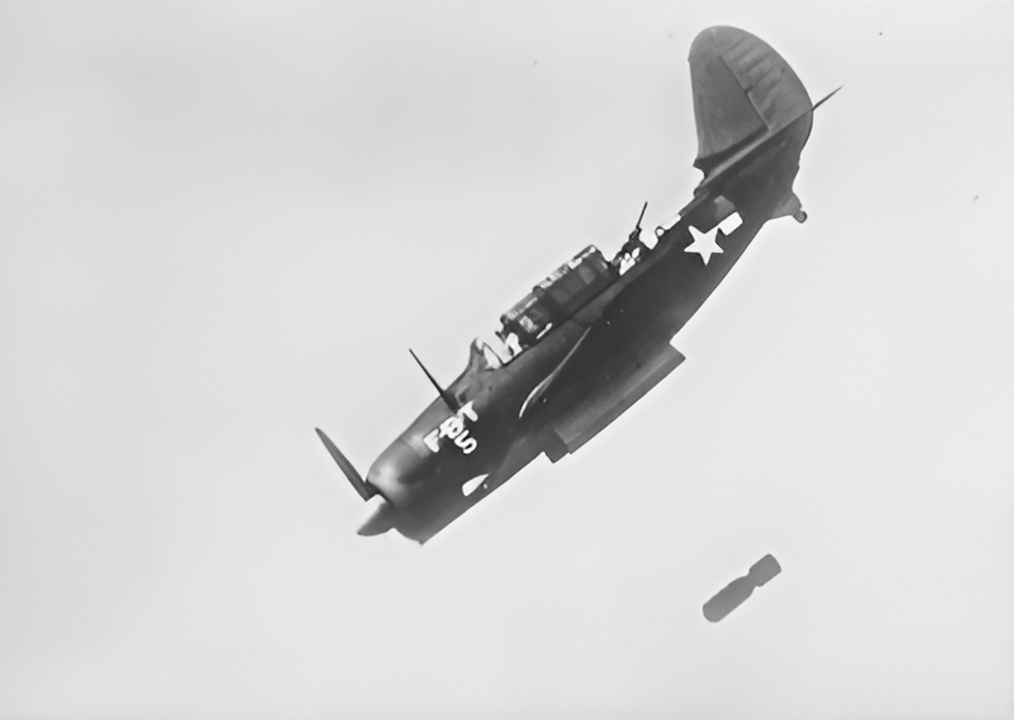 Việc vào pha bổ nhào cuối cùng với góc dốc lớn được bắt đầu ở độ cao không thấp hơn 12.000 ft, tại cự ly ngang khoảng từ ¾ đến ½ dặm so với mục tiêu. Một động tác đẩy mũi xuống (pushover) êm và từ tốn để đưa máy bay vào góc bổ nhào 70 độ, do chỉ huy phi đội thực hiện, là yếu tố then chốt; đồng thời phanh bổ nhào được hạ xuống nhằm đạt tốc độ khoảng 275 dặm/giờ. Mỗi phi công phải tính trước độ lệch ngang để bù cho chuyển động tiến của mục tiêu. Bom được thả ở độ cao từ 2.000 đến 1.000 ft; việc thả dưới 1.000 ft sẽ buộc phải thoát khỏi bổ nhào ở dưới 700 feet, khiến Helldiver gặp nguy hiểm do sóng nổ từ chính quả bom của mình. Sau khi kéo máy bay thoát khỏi bổ nhào, máy bay ném bom bổ nhào thoát ly với tốc độ cao ở độ cao thấp. Bức ảnh này chụp chiếc máy bay Curtiss SB2C-1 Helldiver thả bom, khoảng năm 1943. Chiếc máy bay này, mang mật danh "Fox Baker Tare-5" (FBT-5), được sử dụng để chụp ảnh ném bom bổ nhào nhằm mục đích tuyên truyền. Ngoài ra, có thể thấy cửa khoang chứa bom và phần "lưng rùa" có thể thu vào giữa xạ thủ và đuôi máy bay, giúp xạ thủ có tầm bắn rộng hơn. (Smithsonian National Air and Space Museum)