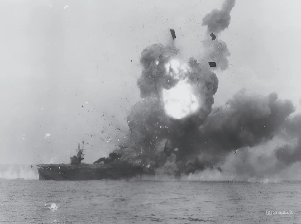 USS St. Lo (CVE-63) được nhìn thấy từ USS Kitkun Bay (CVE-71) ngay sau khi nó bị một chiếc Zero-sen đâm trúng vào ngày 25 tháng 10 năm 1944. Phi công đã tấn công St. Lo thực hiện một cú đánh điêu luyện, tiếp cận từ phía đuôi tàu. Anh ta thả bom trước khi chiếc máy bay đâm vào giữa thân tàu và trượt khỏi boong tàu bay. Quả bom xuyên xuống khoang chứa máy bay và gây ra hỏa hoạn cùng các vụ nổ tại đó, như thể hiện trong hình này. Chưa đầy 30 phút sau khi bị đánh trúng, con tàu lật úp và chìm, khiến 114 thủy thủ thiệt mạng. St. Lo là con tàu đầu tiên bị đánh chìm bởi kamikaze. (NARA)