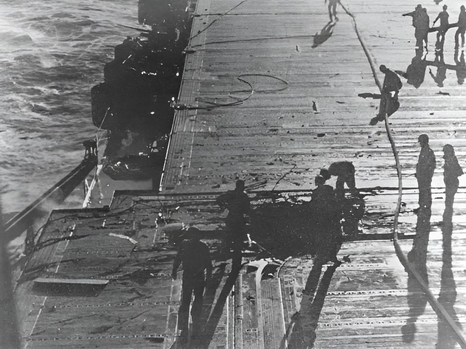 Các thủy thủ đoàn của Enterprise kiểm tra và bắt đầu sửa chữa thiệt hại do quả bom thứ ba đánh trúng sàn bay. (NHHC)