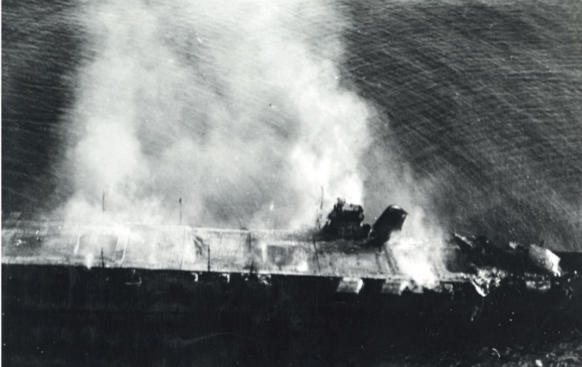 Tây bắc Midway vào sáng ngày 5 tháng 6 năm 1942. Bức ảnh này được chụp bởi một máy bay trinh sát cất cánh từ tàu sân bay Hōshō, thuộc Lực lượng Chủ lực đang di chuyển ở khoảng cách xa phía sau Kidō Butai. Có thể thấy Hiryū đang bốc cháy ngay trước khi bị chìm. Thiệt hại nghiêm trọng đã được gây ra cho phần trước của sàn đáp do bốn quả bom đánh trúng. Vật thể lớn phía trước cấu trúc thượng tầng là một mảnh của thang nâng máy bay số 1 bị hất văng đến vị trí đó bởi sức ép từ các vụ nổ trong nhà chứa máy bay. Các cột ăng-ten dây thường được hạ xuống khi tiến hành hoạt động bay, nhưng trong ảnh có thể thấy chúng được dựng lên. Nhiều khả năng điều này nhằm tránh va chạm với các tàu khu trục tiếp cận bên mạn