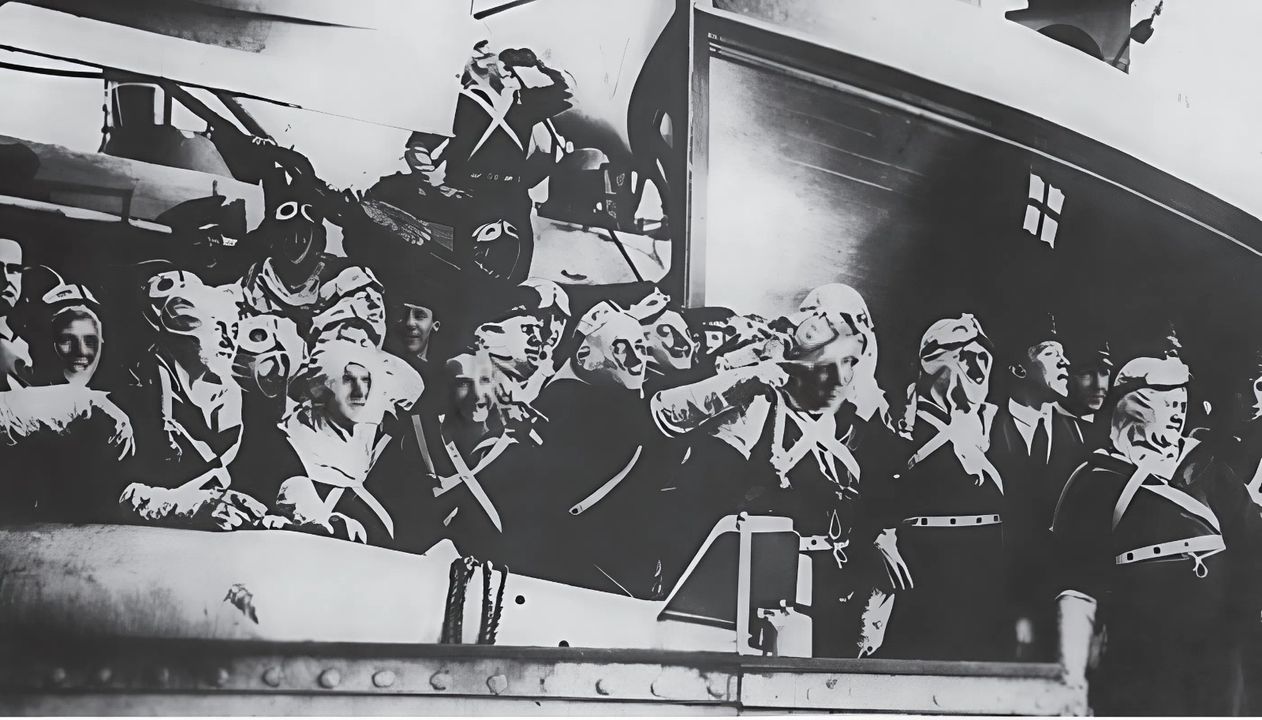 Các thủy thủ Anh, mặc mũ trùm chống cháy, găng tay và kính bảo hộ, đang tựa vào một thiết bị paravane quét mìn trên boong tàu chiến của họ, quan sát cảnh hạm đội Biển khơi Đức đầu hàng vào ngày 21 tháng 11 năm 1918. Phe Đồng minh không hề chủ quan, vì vậy các tàu đều được đặt trong tình trạng sẵn sàng chiến đấu, đề phòng mọi tình huống.