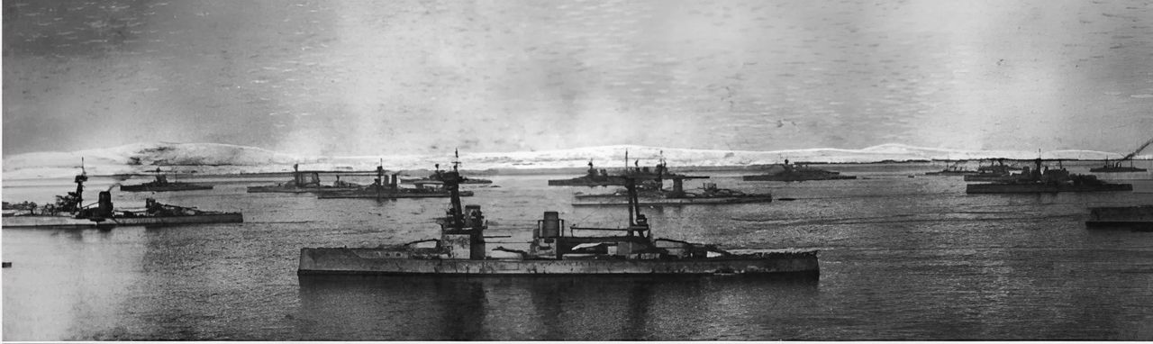 Lực lượng thiết giáp hạm đang neo đậu tại khu neo chính trong mùa đông 1914–15. Góc nhìn từ đảo Flotta, hướng qua Scapa Flow về phía những ngọn đồi Orphir phủ tuyết cách đó khoảng 7 dặm đường bộ về phía đông bắc. Ở tiền cảnh là thiết giáp hạm HMS Neptune.