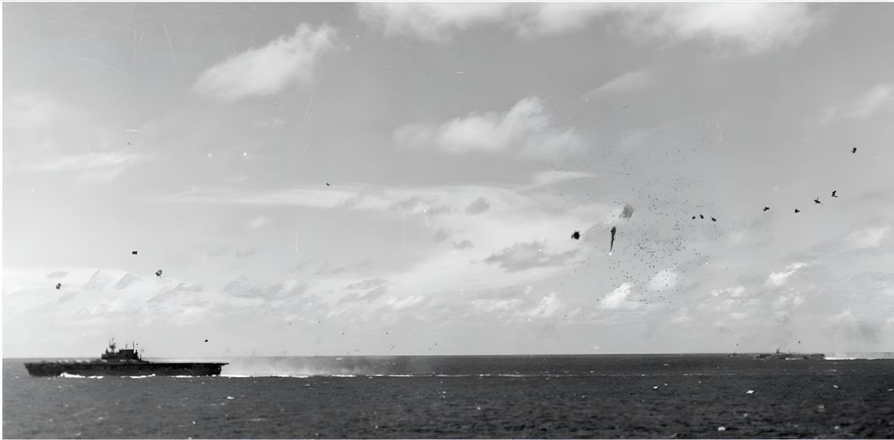 Một số ít máy bay Nhật từ "Đợt Không kích lần II" lọt qua được Hellcat và tiến hành tấn công các tàu sân bay thuộc TG 58.3. Enterprise đang di chuyển tốc độ cao ở bên trái khung hình, còn tàu sân bay ở phía xa là San Jacinto hoặc Princeton. Có thể thấy các đạn nổ 5-inch/38 và pháo 40mm tạo ra những đám khói nổ lớn nhỏ khác nhau. (NHHC)