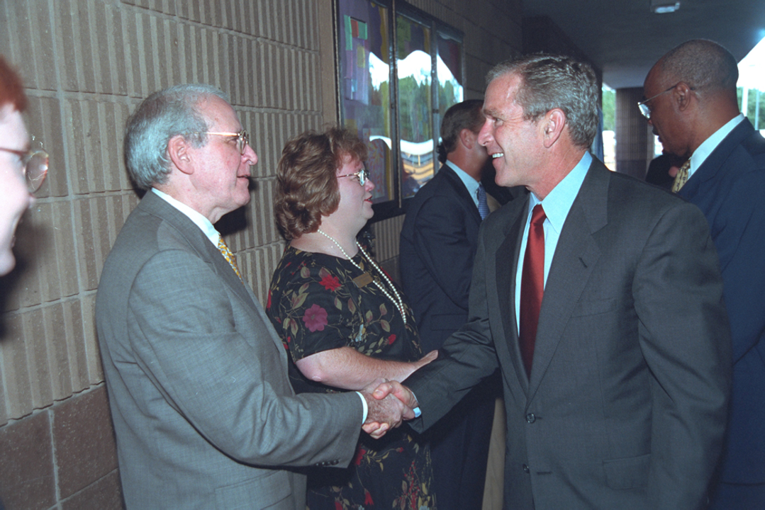 Tổng thống Bush bắt tay với chính trị gia Dan Miller tại hành lang trường. Ảnh của <i>Eric Draper</i>.