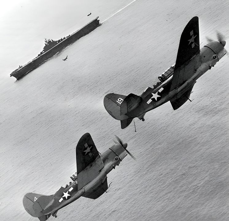 Móc hãm đuôi đã hạ xuống, một biên đội gồm hai chiếc SB2C của VB-17 giữ vị trí trong vòng chờ hạ cánh phía trên tàu Bunker Hill, trong khi các máy bay cùng phi đội lần lượt hạ cánh trở lại sau cuộc đột kích Rabaul vào ngày 11 tháng 11 năm 1943. (Đại úy Robert B. Wood)