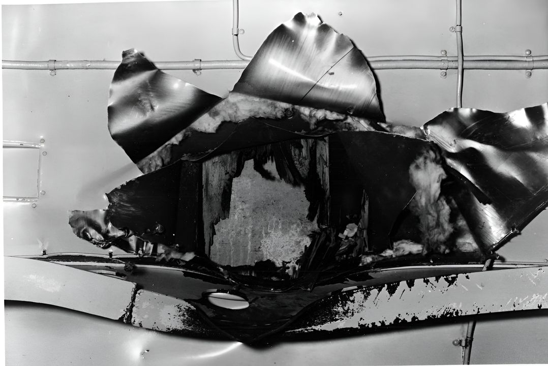 Hình ảnh mặt dưới của cấu trúc sàn đáp, cho thấy lỗ thủng do quả bom Nhật Bản đánh trúng tàu ở giữa tàu trong Trận Biển San Hô, ngày 8 tháng 5 năm 1942. Quả bom đã xuyên thủng nhiều sàn tàu trước khi phát nổ, khiến 66 thủy thủ đoàn thiệt mạng hoặc bị thương nặng. Hình ảnh này nhìn lên trên, với một mảng trên sàn đáp có thể nhìn thấy bên trong lỗ thủng. Chú ý dầm kết cấu ở phần dưới của ảnh, bị biến dạng do quả bom xuyên qua. (NHHC)