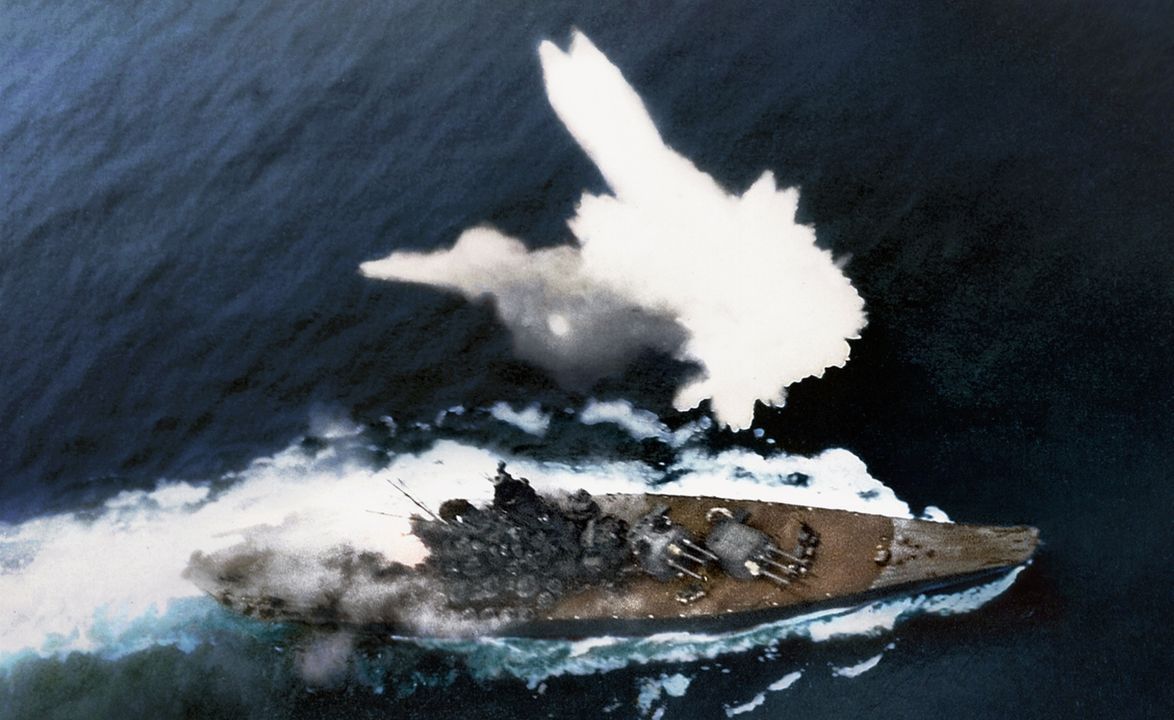 Yamato cơ động một cách tuyệt vọng dưới hỏa lực tấn công khi một quả bom phát nổ bên mạn trái. Có thể thấy rõ đám cháy ở khu vực tháp pháo 6,1 inch phía sau. Lưu ý khói bốc lên từ các bệ pháo 25mm ba nòng. (Naval History and Heritage Command, Photo Archives, Naval Subject Collection)