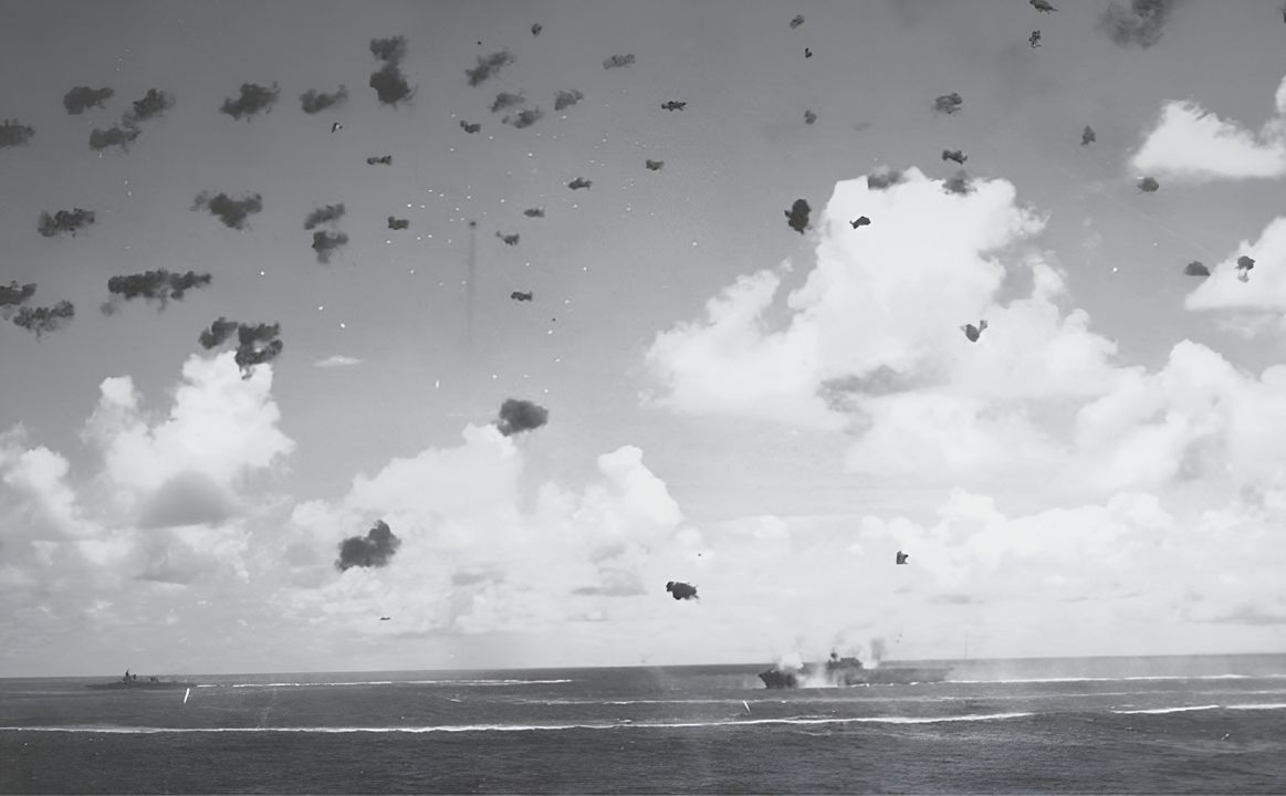 Cuộc tấn công ném bom bổ nhào của Nhật tiếp tục; Enterprise đang thực hiện một cú rẽ gấp sang mạn trái và nghiêng sang mạn phải. Một chiếc Kiểu 99 bị trúng đạn và đang bốc cháy phía trên Enterprise. Mười trong số 19 oanh tạc cơ bổ nhào của Shokaku bị bắn rơi trên Lực lượng Đặc nhiệm 16. (Samuel Morison Collection courtesy of Naval History and Heritage Command)
