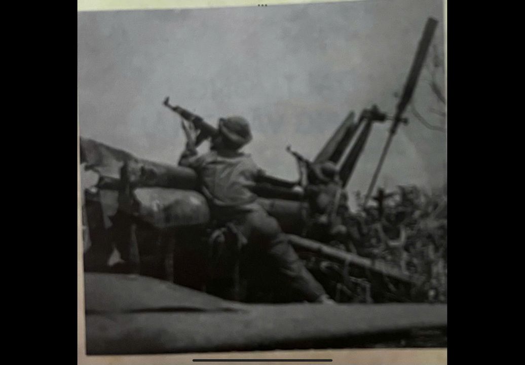 Chiến sĩ Quân giải phóng Đường 9 dùng xác máy bay lên thẳng của địch làm bệ tì để bản may bay dịch. (Ảnh TTXVN)