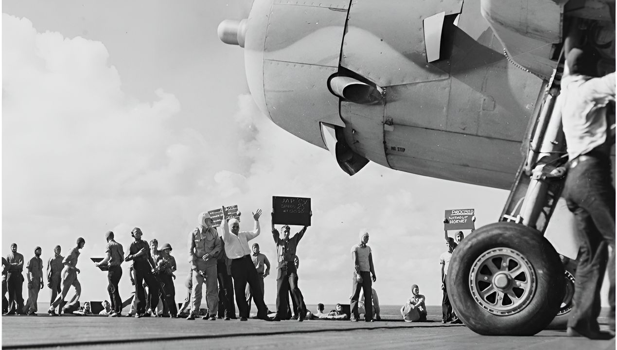 Hoạt động tấn công của Enterprise ngày 26 tháng 10 thiếu phối hợp. Bức ảnh này cho thấy một chiếc Avenger sẵn sàng cất cánh. Các biển báo phía sau làm nổi bật sự nhầm lẫn. Biển bên trái ghi "TÀU SÂN BAY NHẬT TỐC ĐỘ 25 LÚC 08 GIỜ 30 PHÚT" nhưng không cung cấp vị trí mục tiêu cập nhật. Biển bên phải ghi "TIẾN HÀNH KHÔNG CÓ HORNET", xác nhận việc Lực lượng Đặc nhiệm 61 không thể tổ chức các cuộc tấn công phối hợp.