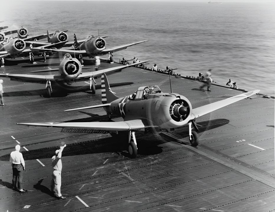 Hình ảnh cho thấy máy bay SBD-3 Dauntless của VB-6 đang chuẩn bị cất cánh trên tàu sân bay USS Enterprise. Chỉ huy nhóm không quân, Trung tá Howard Young đang ở trên máy bay sau, được ký hiệu bằng chữ "GC" (Chỉ huy Nhóm) ở mặt trước mui máy bay. Chú ý đến hệ thống súng máy Browning cỡ nòng 0.50 inch làm mát bằng nước. (NHHC)