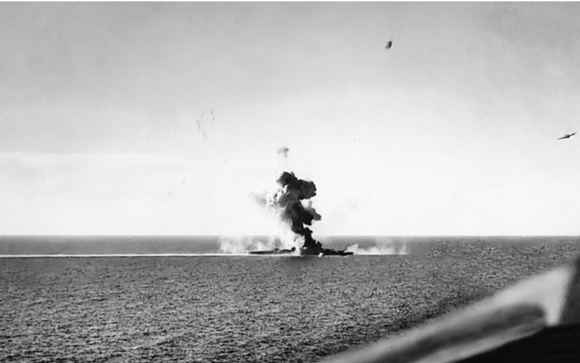 Bức ảnh này cho thấy tàu tuần dương hạng nặng Kumano đang bị tấn công bởi các máy bay Helldiver thả bom 1.000lb vào ngày 26 tháng 10 năm 1944, khi Lực lượng Tấn công thứ nhất rút lui qua Biển Sibuyan. Cuộc giao tranh diễn ra tại eo biển Tablas gần mũi phía nam của đảo Mindoro. Nguồn tin Nhật Bản cho biết ba quả bom (500 pound - nếu đúng, thì đây là từ 12 chiếc F6F Hellcat đã tham gia cuộc tấn công) đã trúng tàu, gây ra thiệt hại nghiêm trọng. Không có chiếc máy bay ném ngư lôi TBM-1C nào tấn công đã ghi được một quả ngư lôi trúng đích. Tàu tuần dương có thể cập cảng và sửa chữa, cung cấp một ví dụ khác về khó khăn trong việc đánh chìm tàu chiến lớn chỉ bằng bom.