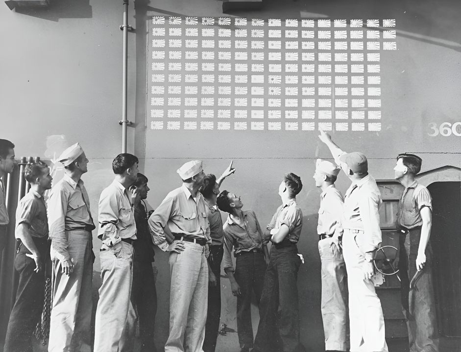 Các sĩ quan và thủy thủ trên Lexington chiêm ngưỡng những lá cờ Nhật Bản, tượng trưng cho 143 máy bay Nhật do Không đoàn 16 (Air Group 16) tuyên bố bắn rơi. Ngoài một máy bay bị mất ngày 19 tháng 6, Không đoàn 16 còn mất ba chiếc do máy bay Nhật bắn hạ và năm chiếc khác do nguyên nhân khai thác/kỹ thuật trong ngày 20 tháng 6 — mức tổn thất nhẹ nhất trong số các tàu sân bay hạm đội tham chiến trong cả hai ngày của trận đánh. Bức ảnh chụp vào ngày 21 tháng 6 năm 1944, ngay sau Trận chiến Biển Philippine (NHHC)