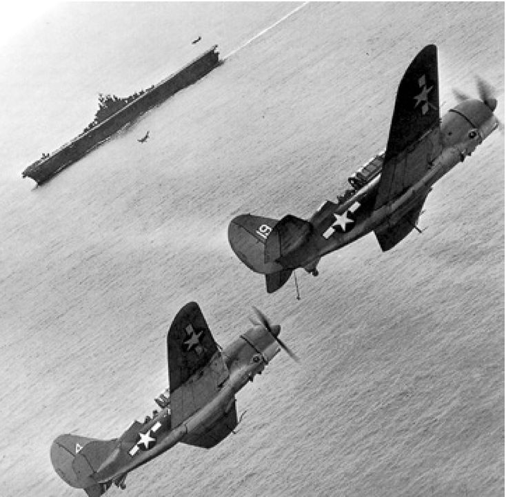 Cánh hãm khóa xuống, một phân đội gồm hai chiếc SB2C từ VB-17 duy trì vị trí trong đường bay hạ cánh phía trên Bunker Hill trong khi các phi công đồng đội hạ cánh trở lại tàu sau cuộc đột kích Rabaul vào ngày 11 tháng 11 năm 1943. (Đại úy Robert B. Wood)