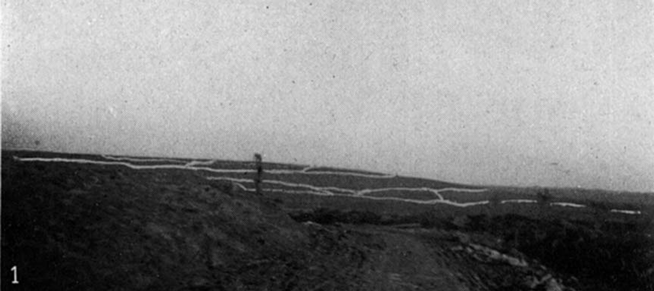 "Góc của Kelly" hoặc "Góc uốn cong của Strafen" trên đường Esnes. Từ xa có thể nhìn thấy Le Mort Homme và chiến hào tuyến đầu của quân Đức. Một loạt đạn pháo đang nổ trên cánh đồng bên phải.