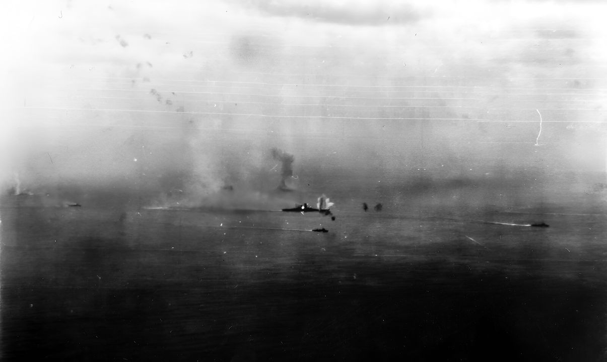 Yamato bị máy bay từ Hornet tấn công trong đợt không kích đầu tiên. Chỉ còn ba tàu khu trục bảo vệ siêu thiết giáp hạm, và có thể thấy rõ số lượng ít ỏi các đám nổ từ pháo 5 inch của Nhật. Một quả ngư lôi hoặc bom vừa phát nổ ở phía trước mạn phải. (Naval History and Heritage Command, Photo Archives, Naval Subject Collection)