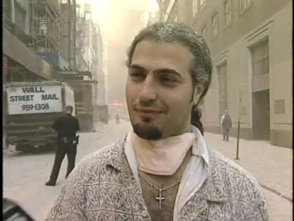 <i>Jack Talierco</i>, đang được phỏng vấn, tầm buổi chiều trước 5h25. WTC5 bốc cháy đằng sau.