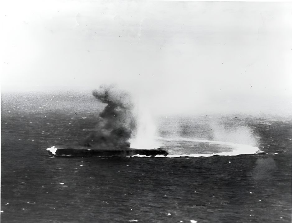 Shokaku thực hiện các động tác cơ động gắt để tránh các đòn tấn công từ các máy bay ném bom bổ nhào của Yorktown. Có thể thấy đám cháy ở phần mũi tàu do quả bom đầu tiên đánh trúng, và cột khói bốc lên cho thấy quả bom thứ hai nặng 1.000 pound đã đánh trúng ngay phía sau đảo chỉ huy. Cú đánh thứ hai gây ra những đám cháy lớn, nhưng các đội kiểm soát hư hại của tàu đã dập tắt được. (NHHC)