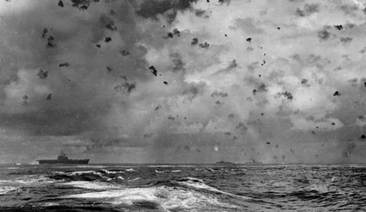 Bức ảnh này được chụp vào ngày 26 tháng 10 năm 1942, ngay lúc cao trào cuộc tấn công bằng máy bay ném bom bổ nhào vào tàu Enterprise trong trận chiến quần đảo Santa Cruz. Nó mô tả sống động cường độ hỏa lực phòng không mà các tàu hải quân Mỹ có thể bắn ra vào giai đoạn này của cuộc chiến Thái Bình Dương. Tàu sân bay nằm ở phía bên trái của hình ảnh, một tàu khu trục xuất hiện ở giữa và tàu South Dakota, ở phía bên phải của ảnh, đang bắn loạt pháo 5 inch/38 bên mạn phải, được đánh dấu bởi ánh lóe sáng rực rỡ. Ít nhất hai chiếc D3A1 có thể nhìn thấy phía trên tàu Enterprise. (NHHC)