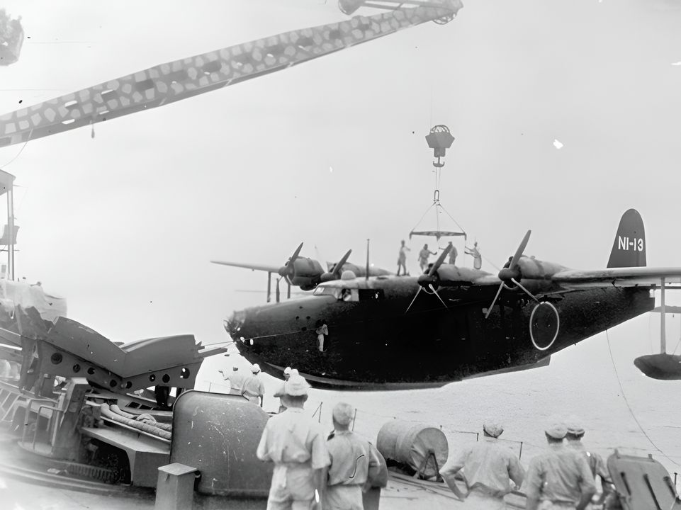 Một chiếc thuyền bay H8K1 Type 97 đang được cần cẩu đưa lên tàu tiếp tế thủy phi cơ Akitsushima vào năm 1942. Chiếc máy bay này có tầm bay phi thường, gần 4.000 hải lý, nhưng vẫn cần một điểm tiếp nhiên liệu để bay tới Trân Châu Cảng từ căn cứ Nhật Bản gần nhất. Kế hoạch lập điểm tiếp dầu trên các đảo hoang giữa Hawaii và Midway đã thất bại, khiến người Nhật không thể tiến hành trinh sát trước trận đánh đối với Trân Châu Cảng. (Yamato Museum)