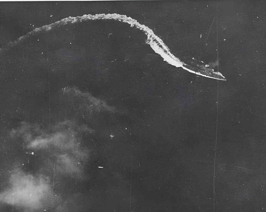 Trong một góc nhìn khác từ một chiếc Avenger của Monterey, một tàu tuần dương hạng nặng Nhật Bản — nhiều khả năng là Maya do có lẽ chỉ có hai tháp pháo 8 inch phía trước — đang cơ động dưới làn tấn công. Con tàu chỉ chịu một cú nổ sượt mục tiêu trong đợt đánh này. (NHHC)