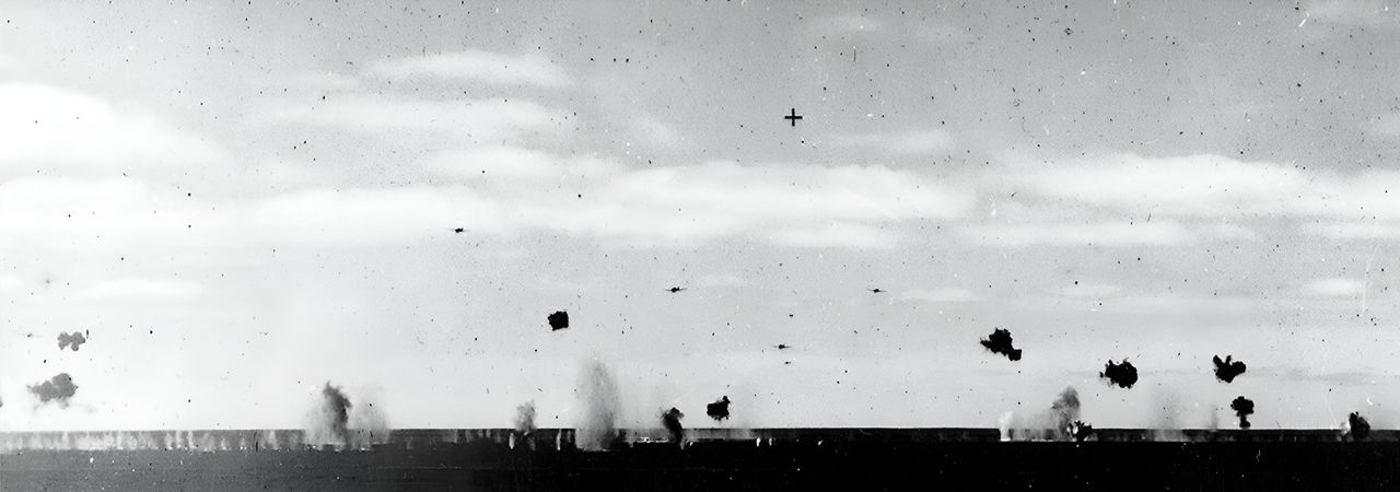 Trong ảnh chụp từ tàu tuần dương hạng nặng Pensacola, nhóm bốn chiếc Type 97 của Tomonaga lao về phía Yorktown. Chú ý hoả lực phòng không dày đặc khi các máy bay tiếp cận tàu sân bay. (NHHC)