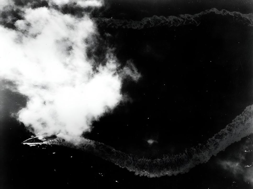 Yamato đang thực hiện các thao tác né tránh với tốc độ từ 15 đến 20 hải lý/giờ trước khi bị tấn công. Có thể quan sát thấy một đám cháy ở giữa thân tàu từ các cuộc tấn công trước đó, nhưng tại thời điểm này, tàu chưa bị nghiêng. (Bộ sưu tập của Đô đốc Hạm đội Chester W. Nimitz, USN)