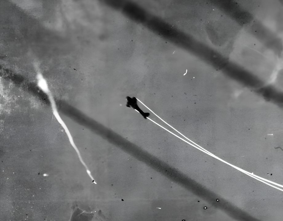 Một ảnh chụp khác từ USS Pensacola rõ ràng hơn về chiếc máy bay Type 99 đang bay qua làn hỏa lực phòng không với dầu máy phun ra và bốc hơi ngay lập tức do nhiệt độ cao, tạo thành vệt khói trắng dày, dài kéo theo từ cánh máy bay. (NHHC)