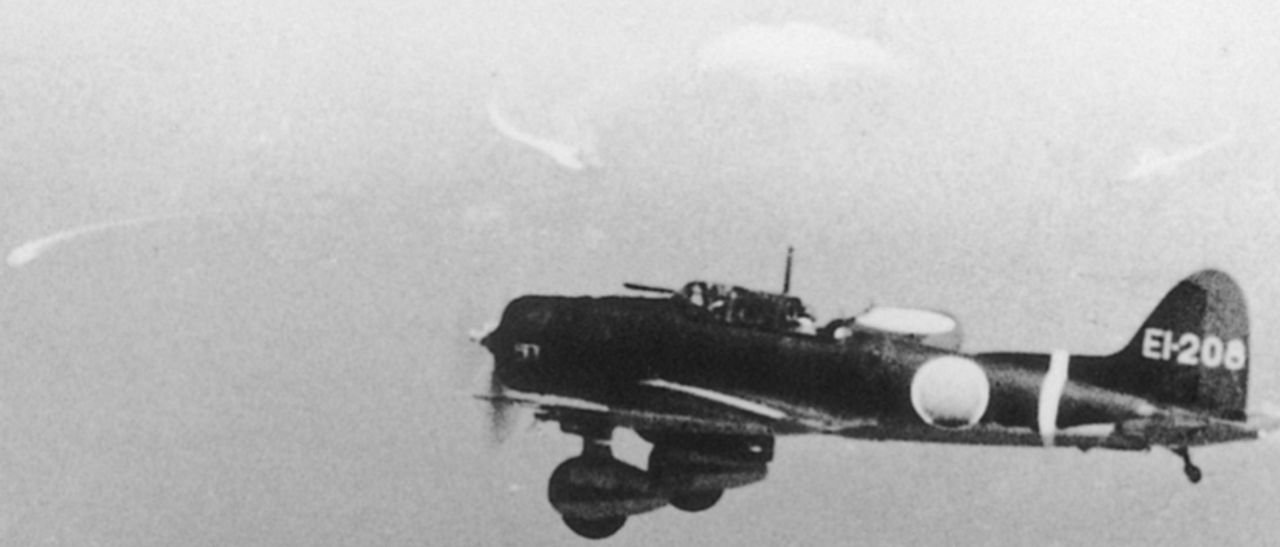 “EI-208” là một trong 19 chiếc D3A1 từ tàu Shokaku đã tấn công tàu Lexington vào ngày 8 tháng 5 năm 1942, máy bay được chụp ảnh ở độ cao 14.000 feet chỉ vài phút trước khi nó nhắm mục tiêu tàu sân bay. Những gì dường như là dấu vết sóng do các tàu cơ động để lại có thể được nhìn thấy phía sau máy bay ném bom lặn. (Bộ sưu tập Tony Holmes)