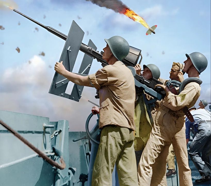 <i>GÓC NHÌN CỦA NGƯỜI MỸ</i>: Trong khung cảnh này, một khẩu pháo 20mm đang khai hỏa vào một tiêm kích Zero-sen có ý định lao vào một tàu sân bay của Hải quân Mỹ. Giá súng đơn này đang bắn từ khu vực phòng pháo ở mép boong tàu sân bay. Khẩu pháo Oerlikon 20mm là loại pháo phòng không được sản xuất nhiều nhất trong lịch sử Hải quân Mỹ, với hơn 88.000 khẩu được chế tạo. Hải quân Mỹ đã tiếp nhận khẩu pháo do Thụy Sĩ thiết kế này vào năm 1941, và loại vũ khí này có nhiều ưu điểm – tốc độ bắn cao 450 phát mỗi phút, nòng súng dễ thay thế và độ tin cậy cao khiến tình trạng kẹt đạn khó xảy ra. Vũ khí này được làm mát bằng không khí và đạn dược được cung cấp bởi các băng đạn tháo lắp chứa 60 viên. Giá súng không cần sử dụng năng lượng, khiến việc bố trí nó ở bất kỳ đâu có góc bắn thoáng trở nên dễ dàng.Việc ngắm và điều khiển được thực hiện bởi pháo thủ sử dụng tay cầm và bệ tỳ vai. Hệ thống ngắm ban đầu là thước ngắm mở, và cứ mỗi năm viên lại có một viên đạn vạch đường để hỗ trợ quan sát. Năm 1942, thước ngắm mở dần được thay thế bởi kính ngắm ổn định hồi chuyển Mk 14, giúp tăng cường đáng kể hiệu quả của khẩu pháo. Tất cả những điều này khiến Oerlikon 20mm trở thành một loại vũ khí hiệu quả để đối phó với các máy bay tấn công thông thường. Tuy nhiên, với đầu đạn chỉ nặng 0,27lb, khẩu pháo này không thích hợp để đối phó với các máy bay cảm tử kamikaze. (Tranh của Jim Laurier)