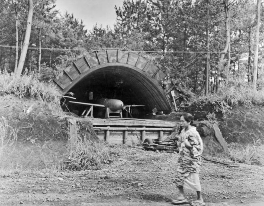 Đến cuối chiến tranh, người Nhật đã kịp triển khai nhiều loại vũ khí đặc công cảm tử khắp đất nước, nhiều cái đặt ngay trong khu dân cư. Trong ảnh, một phụ nữ đi ngang qua một chiếc Oka được cất giữ trong hầm trú ẩn. Bức ảnh chụp tháng 9 năm 1945, ngay sau khi chiến tranh kết thúc. (NARA 80G 375010)