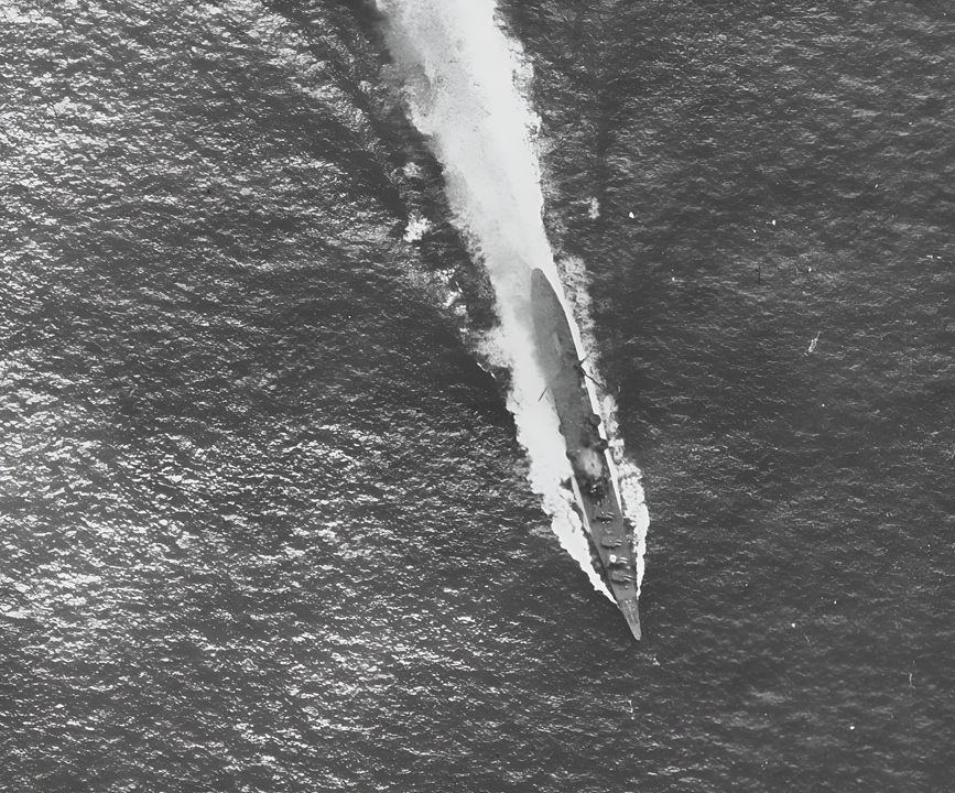 Rất ít cuộc tấn công của máy bay Mỹ vào ngày 26 tháng 10 nhắm vào một tàu sân bay Nhật. Chikuma phải chịu nhiều cuộc tấn công bởi các máy bay không tìm thấy tàu sân bay Nhật. Trong góc nhìn này, tàu tuần dương hạng nặng đang di chuyển với tốc độ cao với tất cả các tháp pháo 8-inch phía trước hướng sang mạn trái. Lưu ý ký hiệu nhận dạng trên không nằm trên tháp pháo thứ hai và cả hai máy phóng đều đã được xoay ra. Con tàu bị trúng một quả bom 1.000 lb trên cấu trúc thượng tầng phía trước, nơi khói rõ ràng trong góc nhìn này. Chikuma sống sót qua trận chiến bất chấp hư hại nặng. Bức ảnh này được chụp từ chiếc Avenger của chỉ huy không đoàn tàu Hornet, Chỉ huy Rodee.