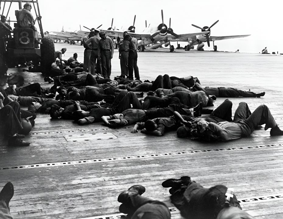 Nhân viên điều phối máy bay trên Lexington nghỉ ngơi trên sàn bay trong một quãng tạm lắng của trận đánh ngày 19 tháng 6. Các máy bay ở hậu cảnh là Hellcat của VF-16. Phi đội này đã thực hiện 38 phi vụ trong ngày và tuyên bố bắn rơi 26 máy bay Nhật Bản. Một chiếc Hellcat bị mất do nguyên nhân kỹ thuật/khai thác. (NHHC)